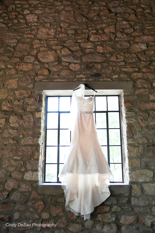 wedding dress hangs from barn window